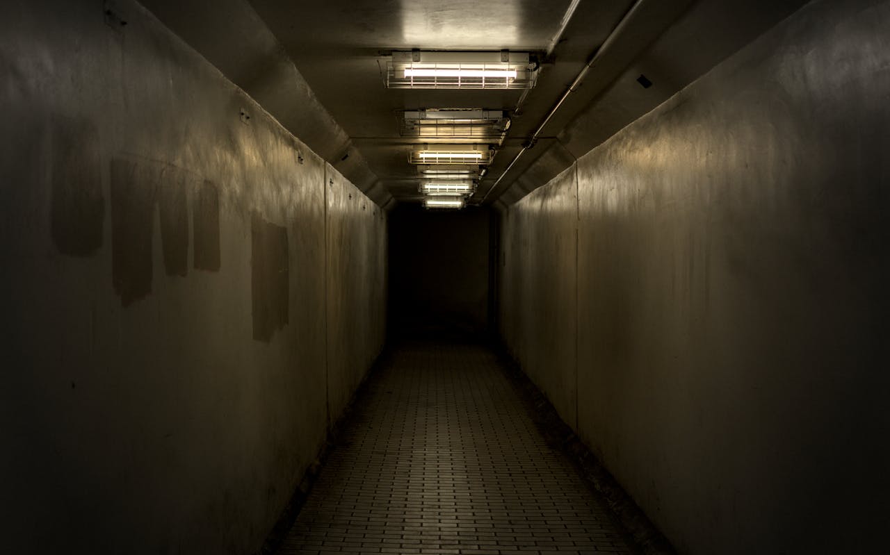 Moody and dark image of an empty underground tunnel with fluorescent lights.
